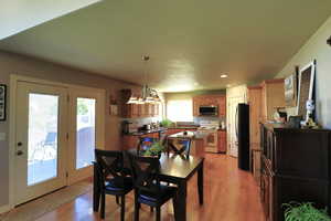 Dining area featuring light wood-type flooring, a notable chandelier, and plenty of natural light