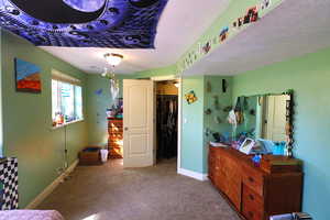 Carpeted bedroom featuring a textured ceiling and a closet