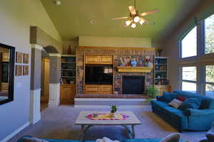 Living room with a healthy amount of sunlight, a fireplace, ceiling fan, and high vaulted ceiling