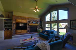 Living room featuring high vaulted ceiling, ceiling fan, light colored carpet, and a fireplace