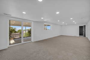 Spare room with a textured ceiling, a healthy amount of sunlight, and light colored carpet