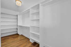 Spacious closet with wood-type flooring and a chandelier