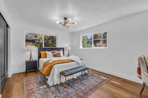 Bedroom with a textured ceiling, hardwood / wood-style floors, a notable chandelier, and a closet