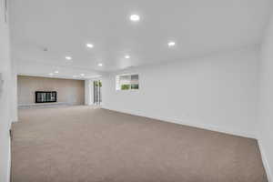 Unfurnished living room featuring brick wall, light carpet, and a brick fireplace