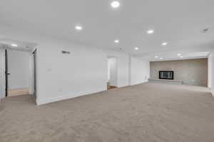 Unfurnished living room featuring brick wall, light carpet, and a brick fireplace