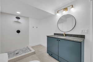 Bathroom with a textured ceiling, vanity, tiled shower, tile patterned flooring, and toilet