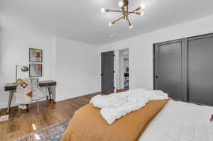 Bedroom with hardwood / wood-style floors, an inviting chandelier, and a closet