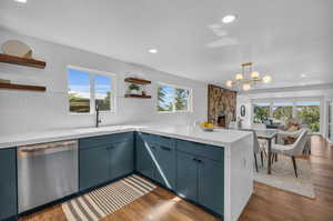 Kitchen with dark hardwood / wood-style flooring, a notable chandelier, sink, blue cabinets, and stainless steel dishwasher