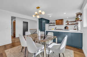 Dining room featuring sink, wood-type flooring, and a chandelier