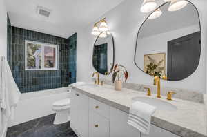 Full bathroom featuring vanity, toilet, an inviting chandelier, and tiled shower / bath