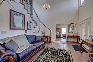 Tiled living room with a high ceiling and a notable chandelier