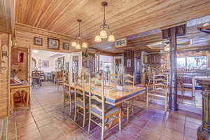 Tiled dining space featuring wooden ceiling and wood walls