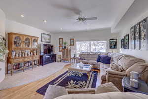 Living room with ceiling fan and hardwood / wood-style flooring