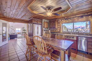 Dining room featuring wood ceiling, ceiling fan, light tile patterned flooring, and a healthy amount of sunlight