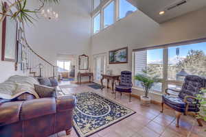 Living room with a high ceiling, a notable chandelier, and light tile patterned flooring