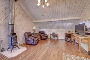 Sitting room featuring wood ceiling, light hardwood / wood-style flooring, a wood stove, and lofted ceiling with beams