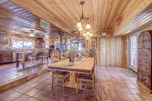 Dining space with tile patterned flooring, wood walls, wood ceiling, and ceiling fan