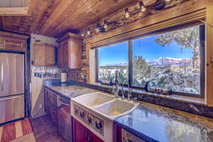 Kitchen featuring wooden ceiling, dark tile patterned flooring, stainless steel appliances, a mountain view, and sink