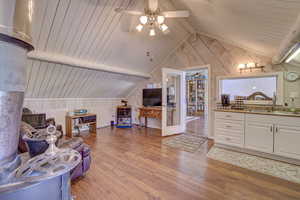 Interior space featuring hardwood / wood-style floors, sink, wood walls, ceiling fan, and vaulted ceiling with beams