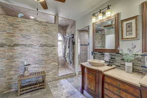 Bathroom featuring tiled shower, vanity, ceiling fan, and decorative backsplash