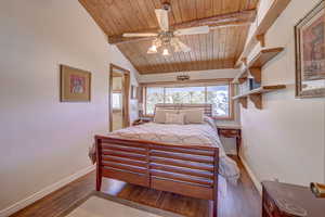 Bedroom with ceiling fan, dark hardwood / wood-style floors, wooden ceiling, and lofted ceiling with beams