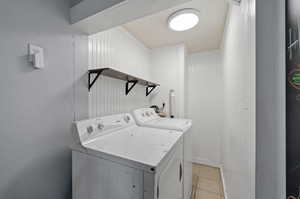 Laundry area with light tile patterned flooring and washer and dryer