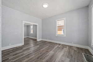 Spare room with a textured ceiling and dark hardwood / wood-style flooring