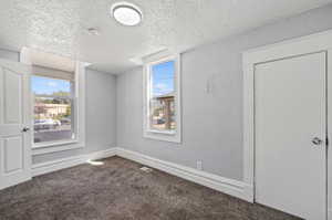 Empty room with a textured ceiling and carpet flooring