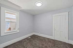 Empty room featuring a textured ceiling and carpet floors