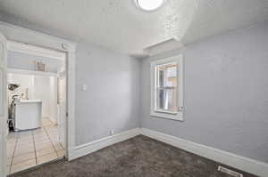 Empty room featuring carpet flooring and a textured ceiling