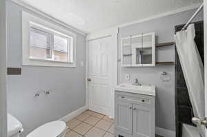 Full bathroom featuring toilet, tile patterned floors, vanity, a textured ceiling, and shower / tub combo