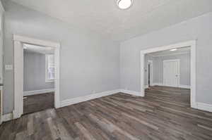 Empty room with a textured ceiling and dark hardwood / wood-style floors