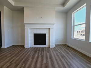 Unfurnished living room with dark wood-type flooring and a tiled fireplace