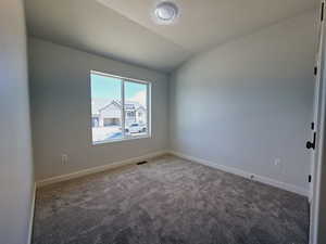 Unfurnished room with lofted ceiling, dark carpet, and a textured ceiling