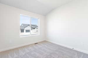 Carpeted empty room featuring vaulted ceiling