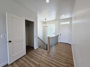 Hall featuring hardwood / wood-style flooring, a chandelier, and a textured ceiling