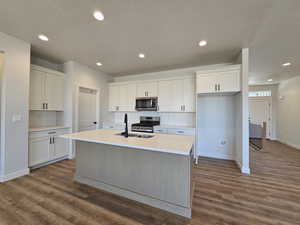 Kitchen featuring a kitchen island with sink, appliances with stainless steel finishes, sink, and white cabinets