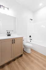 Full bathroom with shower / washtub combination, vanity, toilet, and hardwood / wood-style flooring