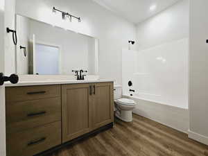 Full bathroom with shower / tub combination, wood-type flooring, toilet, and vanity