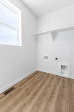 Clothes washing area featuring light wood-type flooring, hookup for a washing machine, and electric dryer hookup