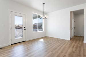 Unfurnished dining area featuring a notable chandelier and light wood-type flooring