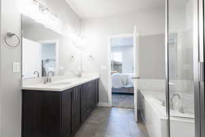 Bathroom featuring vanity, a relaxing tiled tub, and tile patterned floors