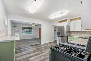 Kitchen featuring white cabinetry, decorative backsplash, ceiling fan, appliances with stainless steel finishes, and light hardwood / wood-style floors