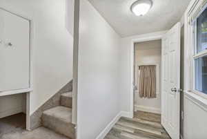 Stairs with a textured ceiling and hardwood / wood-style floors