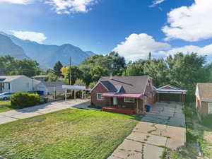 View of front of property with a mountain view, a front yard, and a carport