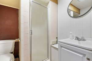 Bathroom featuring vanity, toilet, and a shower with shower door