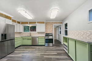 Kitchen with appliances with stainless steel finishes, white cabinetry, light hardwood / wood-style flooring, and green cabinets