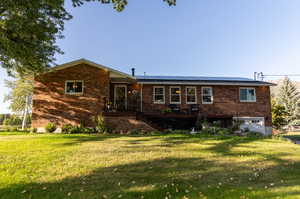 View of front of home with a front yard and solar panels