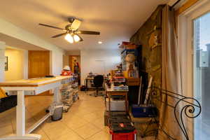 Basement family room featuring a ceiling fan, and fireplace with wood burning stove.