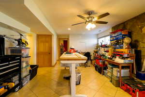 Basement family room with a ceiling fan, and light tile patterned flooring